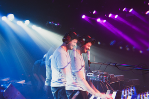 Two musicians on stage with electronic instruments under colorful lights